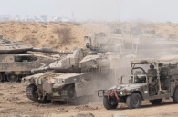 Des soldats israéliens se déplacent avec un véhicule militaire près de chars israéliens près de la frontière avec la bande de Gaza, vus depuis une position du côté israélien de la frontière