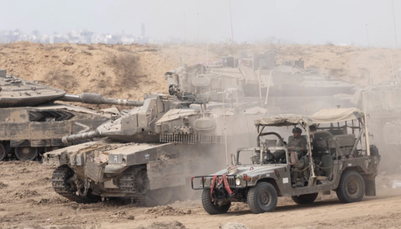Des soldats israéliens se déplacent avec un véhicule militaire près de chars israéliens près de la frontière avec la bande de Gaza, vus depuis une position du côté israélien de la frontière